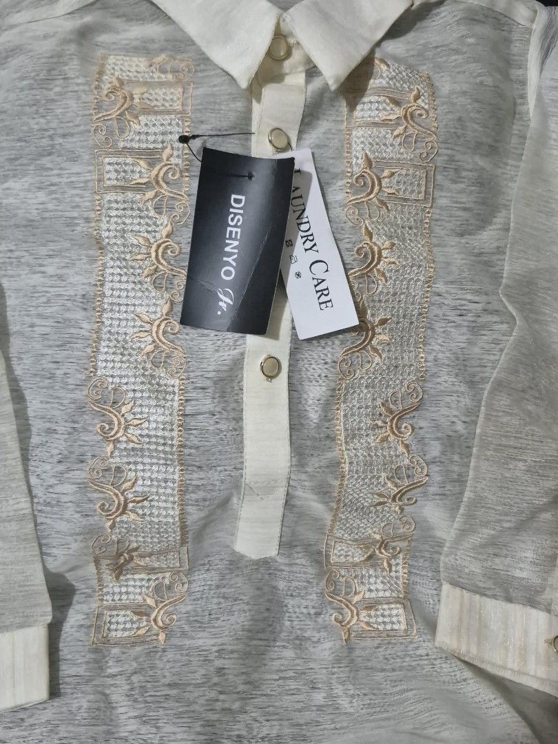 Disenyo Jr. Barong Tagalog (Category: Formal Shirts) located in Quezon City. Submitted by kctheexplorer05 (Listing ID 1470533121, Image 2). Description: Disenyo Jr. Barong Tagalog from Robinsons Department Store. Traditional long-sleeve formal wear. Detailed embroidery panels down the front. Classic pointed collar, button placket, and button cuffs. Cream-colored sheer fabric. Original tags still attached with retail price of P899.00. Size 10 tag 