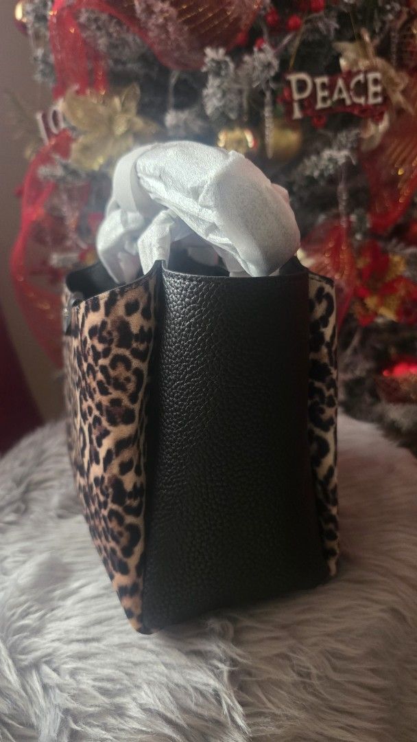DKNY Leopard Print Handbag (Category: Luxury Bags & Wallets) located in Cabanatuan. Submitted by belle_1013 (Listing ID 1470424507, Image 3). Description: - Brand: DKNY - Condition: Brand new, unused with protective packaging and handle wrapping still intact - Design: Structured silhouette combining textured black leather and trendy leopard print panels - Details: Distinctive metal logo badge on the front closure tab with solid black side gussets