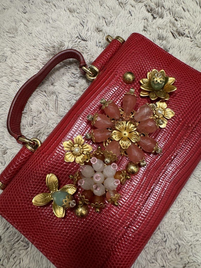 Dolce & Gabbana Purse (Category: Purses & Pouches) located in Antipolo. Submitted by nathshn_ (Listing ID 1470402109, Image 1). Description: Authentic Dolce & Gabbana red textured leather bag with stunning floral crystal embellishments and gold hardware. Features a structured top handle, flap snap closure, and interior card slots. Comes complete with authenticity card. Perfect statement piece for any outfit! Does not come with the original strap 