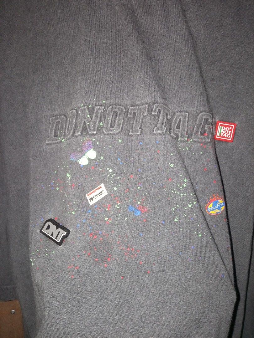 DONOTTAG Graphic Oversized T-Shirt (Category: Tshirts & Polo Shirts ) located in Carmen. Submitted by kyntmiras_thrift (Listing ID 1470456865, Image 3). Description: - Brand: DONOTTAG - Color: Dark grey with washed faded look - Fit: Relaxed, oversized - Material: Comfortable cotton - Design: Large embossed chest logo with colorful splatter graphics and small embroidered patches - Condition: Clean inside and out, ready to wear.