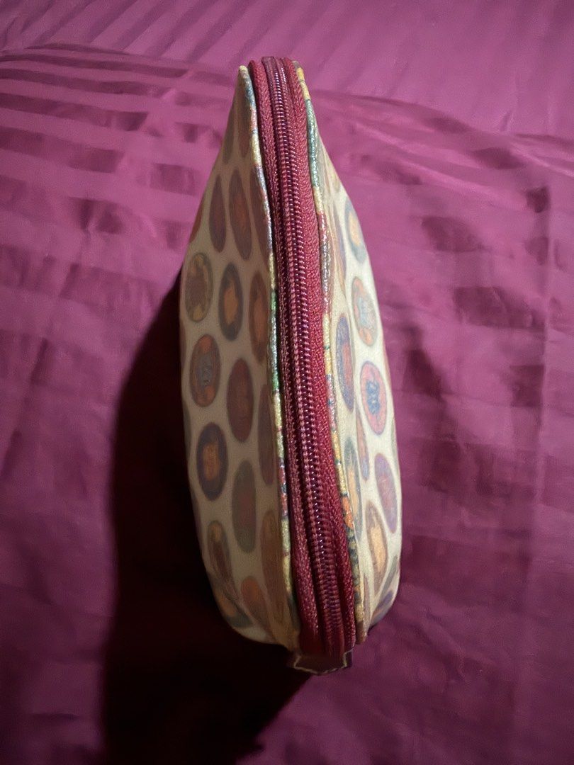 Dooney & Bourke Multicolored Coin Print Cosmetic Pouch (Category: Purses & Pouches) located in Las Pinas. Submitted by ces0427 (Listing ID 1470470692, Image 3). Description: - Authentic Dooney & Bourke cosmetic pouch - Multicolored circular coin and crest print on a cream base with brown trim - Secure zip-top closure with dark red zipper fabric - Bright red fabric interior lining equipped with a convenient slip pocket - Structured base to hold it