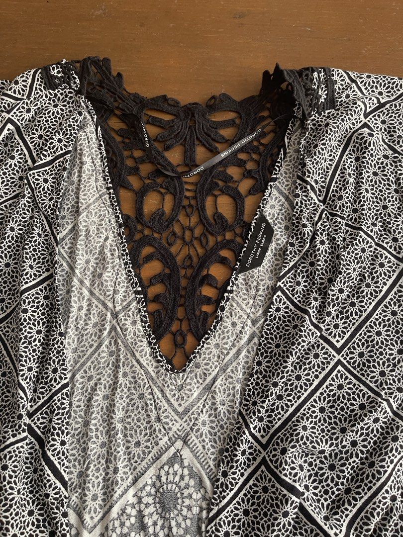 Dorothy Perkins Black And White Patterned Poncho Cape (Category: Coats, Jackets and Outerwear) located in Mandaluyong City. Submitted by coolmeybab (Listing ID 1470360939, Image 2). Description: - Brand: Dorothy Perkins - Size: Large - Design: Black and white geometric and floral pattern with open-front cape style - Details: Intricate black lace detailing down the back center and neckline - Material: Lightweight fabric - Perfect for: Beach trips,
