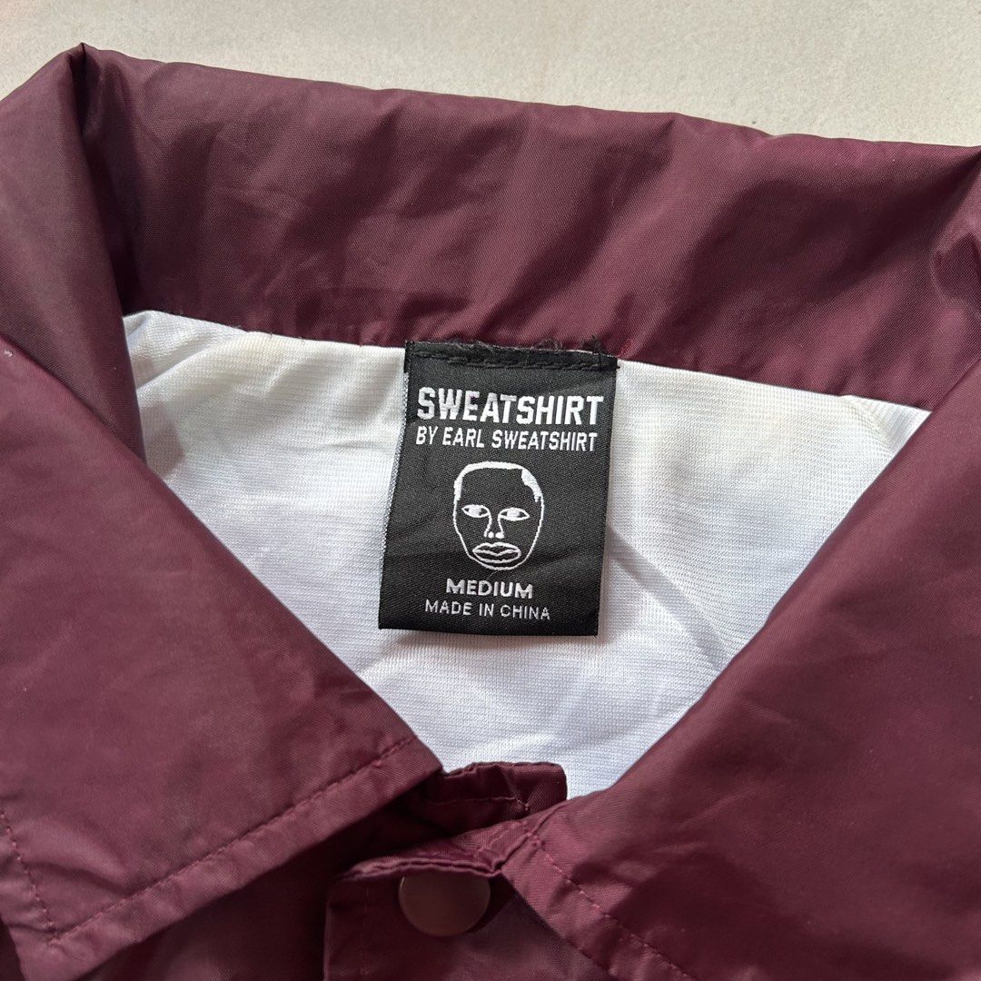 Earl Sweatshirt 1994 Coach Jacket 🥵 (Category: Coats, Jackets and Outerwear) located in Jinoba-an. Submitted by eegiboy (Listing ID 1470397506, Image 2). Description: - Item: Official Earl Sweatshirt Coach Jacket - Color: Maroon - Size: Medium - Details: White graphic face print on chest, bold '1994' print on back - Features: Snap button closure, pointed collar, elasticated cuffs - Material: 100% nylon shell with polyester lining Wts: 34rL Sweat