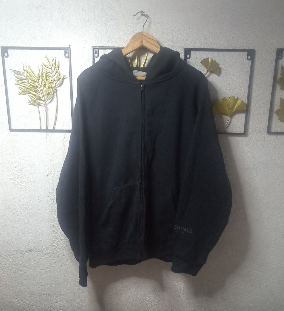 Essentials Hoodie (Category: Hoodies) located in Kawit. Submitted by deidzdzn (Listing ID 1470463930, Image 2). Description: Essentials Fear of God zip-up hoodie in black. Size XL. Measures 25 inches width by 28 inches length. Full front zip, hood with rubber brand patch on the back. Essentials logo printed on the left sleeve and back. ISSUE: NO WASH TAG OFF/LEGIT.