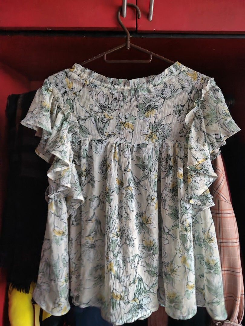 EVALT Floral Ruffle Blouse (Category: Blouses) located in Caloocan City. Submitted by MovesLikeJeager (Listing ID 1470389687, Image 2). Description: EVALT floral blouse in white with green and yellow flowers. Pleated fabric with short ruffled sleeves. Scoop neckline with a drawstring tie in front. Lightweight and flowy material. Easy to match with jeans or skirts for daily wear. Tag shows 100% polyester..