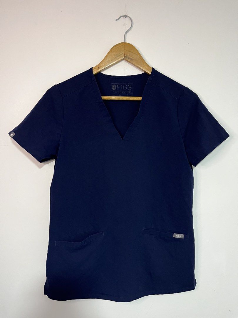 FIGS Technical Collection Navy Blue Scrubs Top V-Neck (Category: Activewear) located in Dasmarinas. Submitted by thriftedbygii (Listing ID 1470532979, Image 1). Description: - Brand: FIGS (Technical Collection) - Color: Navy Blue - Size: Small - Design: Short sleeves, V-neck cut - Features: Two front utility pockets with FIGS logo tag, small cross logo on sleeve cuff - Material: Comfortable, high-performance medical wear fabric - Condition: Clean