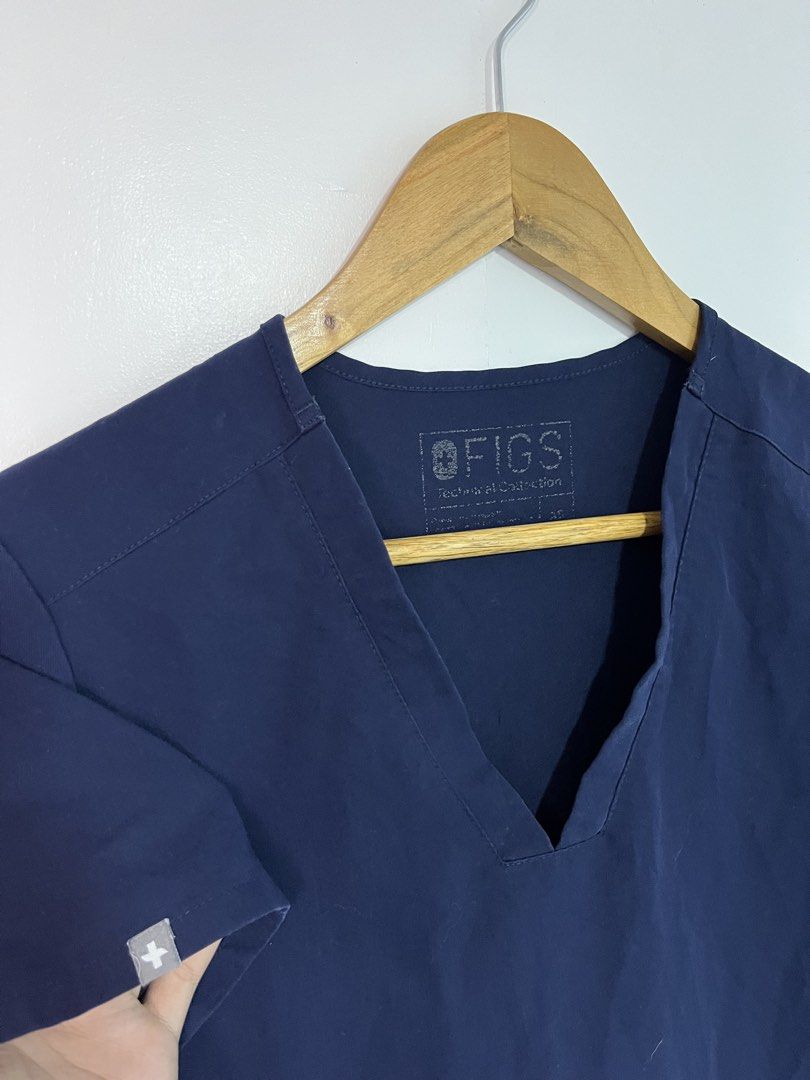 FIGS Technical Collection Navy Blue Scrubs Top V-Neck (Category: Activewear) located in Dasmarinas. Submitted by thriftedbygii (Listing ID 1470532979, Image 2). Description: - Brand: FIGS (Technical Collection) - Color: Navy Blue - Size: Small - Design: Short sleeves, V-neck cut - Features: Two front utility pockets with FIGS logo tag, small cross logo on sleeve cuff - Material: Comfortable, high-performance medical wear fabric - Condition: Clean
