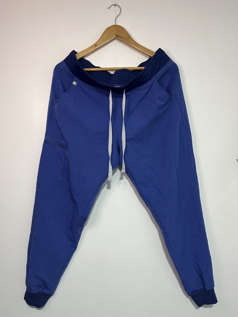 FIGS Technical Collection Scrub Joggers Blue Size L (Category: Joggers) located in Dasmarinas. Submitted by thriftedbygii (Listing ID 1470532986, Image 1). Description: - Brand: FIGS Technical Collection - Color: Blue with contrast dark waistband and cuffs - Fit: Jogger style with secure drawstring waist and ribbed ankle cuffs - Storage: Multiple functional pockets for tools, phone, and essentials - Fabric: Ultra-soft stretch material designed fo