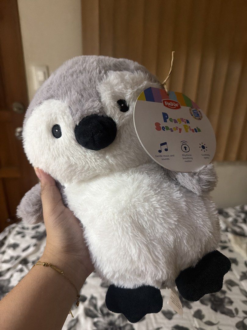 Findon Penguin Sensory Plush (Category: Plushies & Soft Toys) located in Taguig. Submitted by santoes (Listing ID 1470387957, Image 1). Description: - Brand: Findon Penguin Sensory Plush Toy - Design: Soft grey and white fur with black feet and beak - Interactive Features: Plays gentle music/sounds, makes rhythmic breathing movements, and features soothing lights - Ideal For: Comfort toy for babies or toddlers.