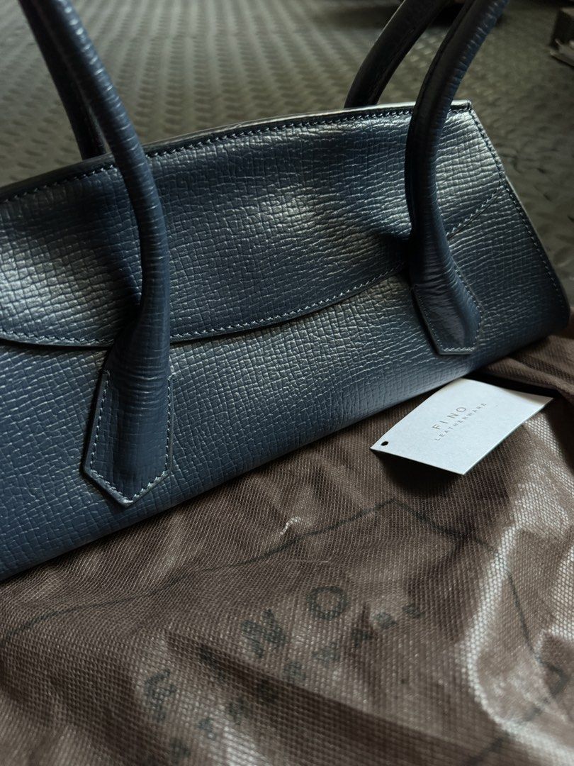 Fino Leatherware Mini Yorker Navy Blue Shoulder Bag (Category: Shoulder Bags) located in Quezon City. Submitted by cheekbuns (Listing ID 1470364702, Image 3). Description: - Brand: Fino Leatherware - Style: Structured east west shoulder bag 12 x 5.5 x 4.5 x 10” - Material: Premium textured blue leather - Features: Double top handles, clean flap closure, pristine interior and exterior - Inclusions: Original dust bag and attached brand tag.
