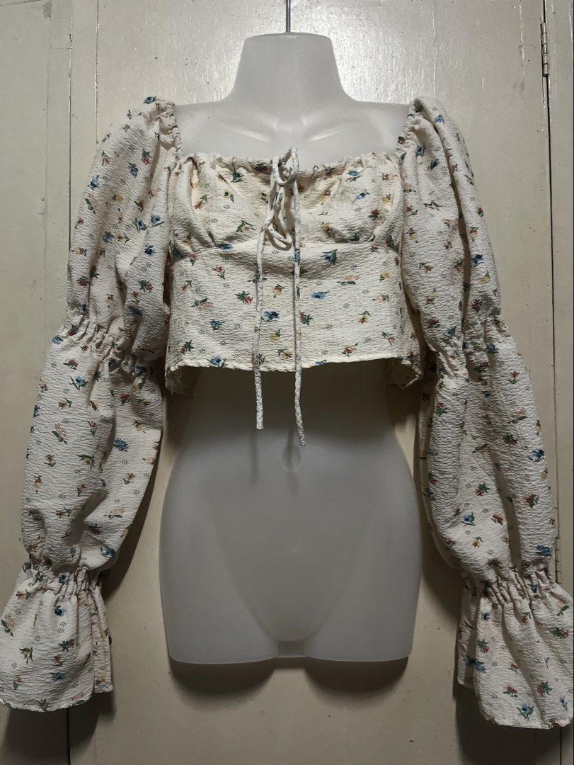 Floral Long Sleeve Crop Top with Drawstring (Category: Longsleeves) located in Tabuk. Submitted by zenwolf-1867 (Listing ID 1470531887, Image 2). Description: - Color: Cream with multicolored floral print - Fit: Crop top, hits right above the waist - Sleeves: Long balloon sleeves with ruffled cuffs - Neckline: Square neckline with front drawstring tie - Details: Elastic shoulders and textured crinkled fabric.