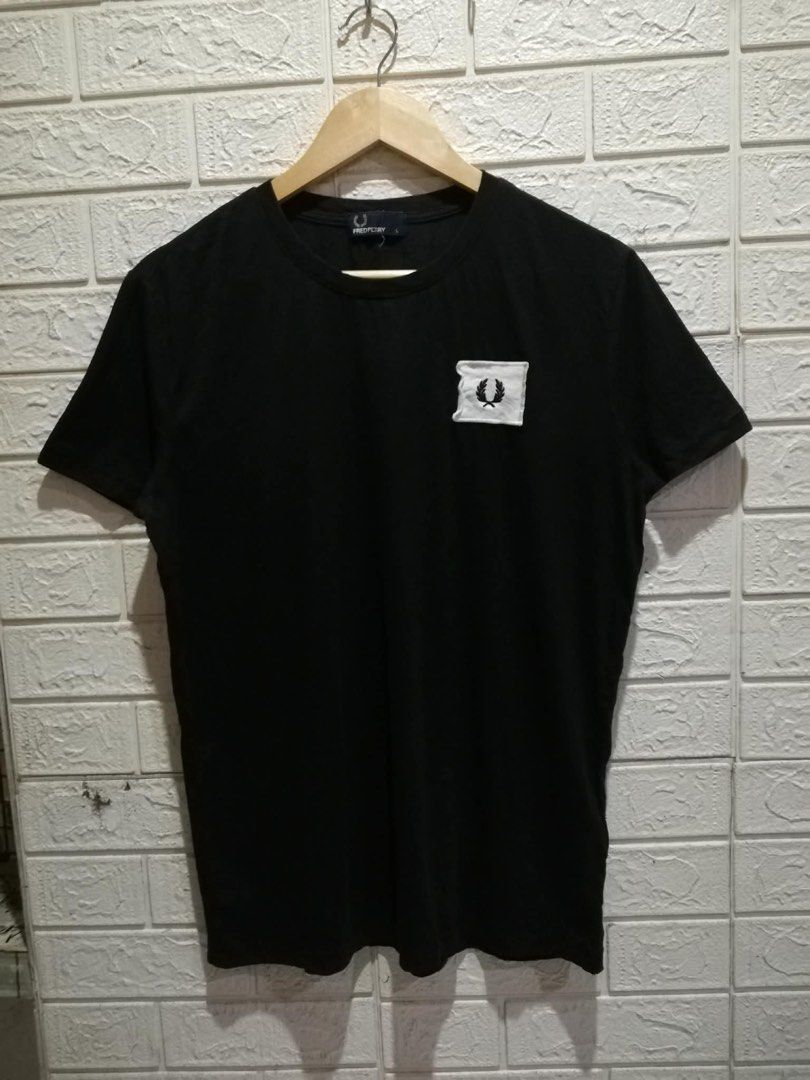 Fred Perry Black T-Shirt with White Patch Logo (Category: Tshirts & Polo Shirts ) located in Rizal. Submitted by tiangarcia02 (Listing ID 1470521465, Image 1). Description: Black crew neck t-shirt from Fred Perry. Short sleeves, standard fit. Features a white square patch on the left chest with the embroidered laurel wreath logo. Inside neck tag and long care label attached at the side seam. Made in China. Clean condition overall, comfortable cot