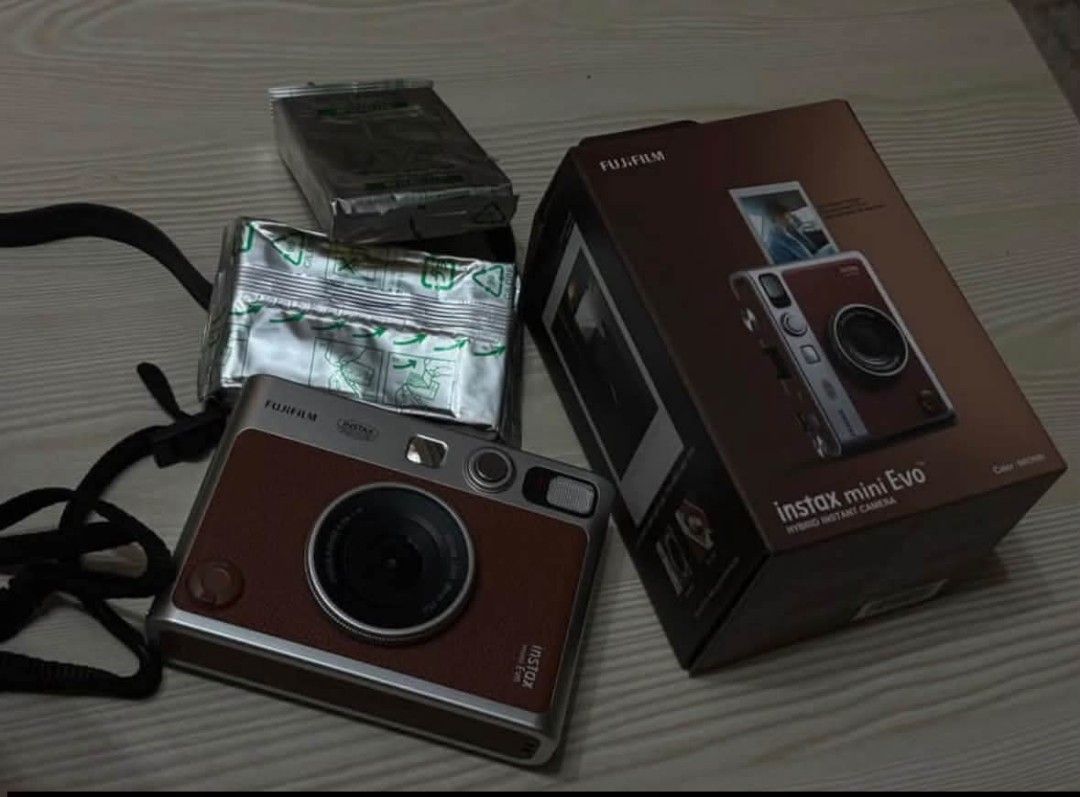 Fujifilm Instax Mini Evo Hybrid Instant Camera (Category: Cameras) located in Cavite. Submitted by adsartes (Listing ID 1470425338, Image 1). Description: - Model: Fujifilm Instax Mini Evo Hybrid Instant Camera - Color: Brown and Silver - Condition: Fully assembled and ready to shoot - Inclusions: Original retail box, shoulder strap, and 2 unopened packs of instant film foil packages - Features: Hybrid setup that lets you shoot digitally and prin