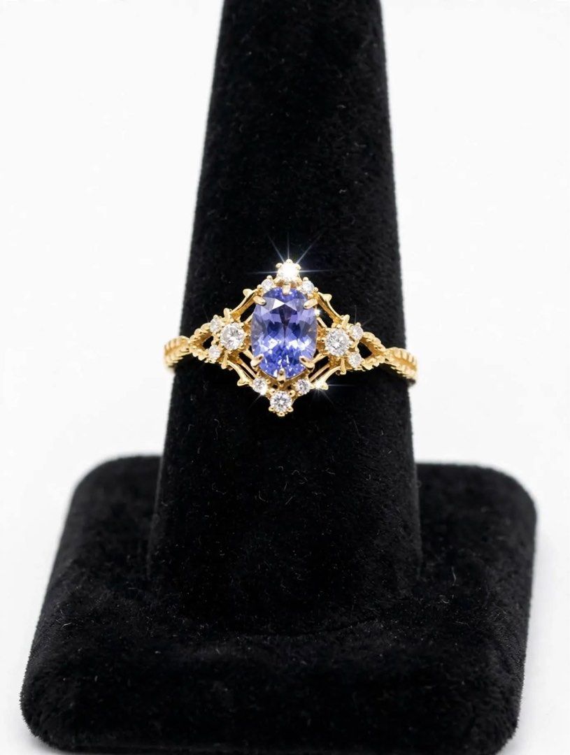 Gold Oval Blue Gemstone Ring with Accent Diamonds (Category: Rings) located in Pasig City. Submitted by treefairyapple (Listing ID 1470351607, Image 2). Description: - Elegant gold ring with a central oval natural tanzanite gemstone - Surrounded by a sparkling cluster of small accent natural diamonds - Unique twisted textured pattern along the band sides - Clean metal finish with securely set stones - Comes with a luxurious cream velvet presentat