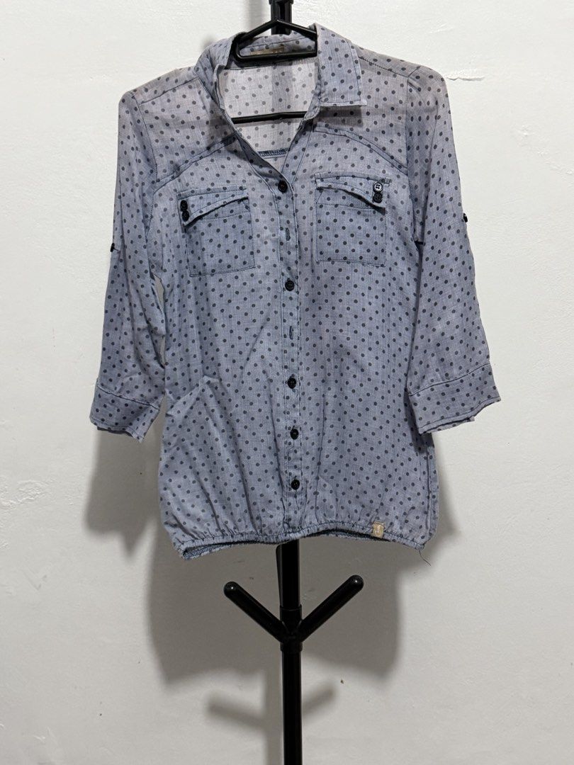 Grey Polka Dot Button-Down Blouse With Pockets (Category: Blouses) located in Mandaluyong City. Submitted by jdflores17 (Listing ID 1470456690, Image 1). Description: - Color: Grey with small dark polka dots - Style: Button-down blouse with pointed collar - Sleeves: 3/4 sleeves with convenient roll-up tabs - Details: Dual chest pockets with button flaps - Fit: Elasticized hem for a stylish blouson effect - Fabric: Lightweight and comfortable for 