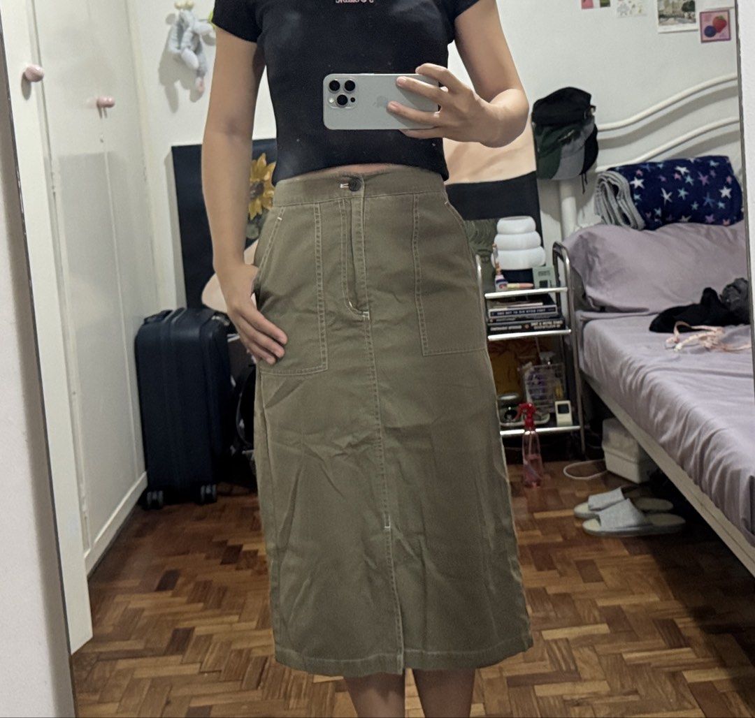 GU Olive Green Midi Skirt with Pockets (Category: Skirts) located in Angeles City. Submitted by m1lkramen (Listing ID 1470470181, Image 2). Description: - Color: Olive green - Style: High-waisted midi skirt with straight cut - Details: Front button closure, contrast stitching, and front hem slit - Pockets: Large utility pockets on both sides - Material: Sturdy, high-quality cotton - Condition: Brand new / Excellent - Perfect for: Casual everyday 