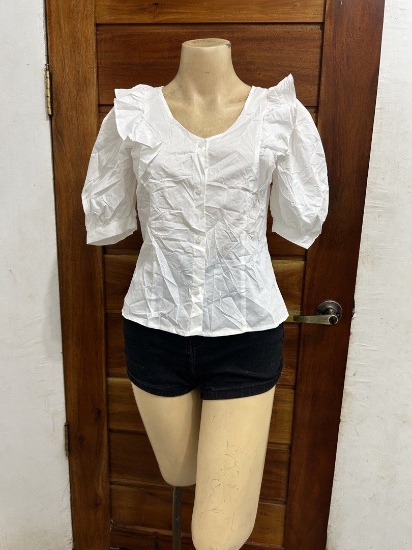 GU White Ruffle Puff Sleeve Button-Up Blouse Size S (Category: Blouses) located in Valencia. Submitted by crizzagella20 (Listing ID 1470545796, Image 1). Description: - Brand: GU - Size: Small - Color: White - Material: Cotton and polyester blend - Design: V-neck with front buttons - Details: Short puff sleeves with ruffle trim along shoulders and neckline - Condition: Clean and ready to wear.