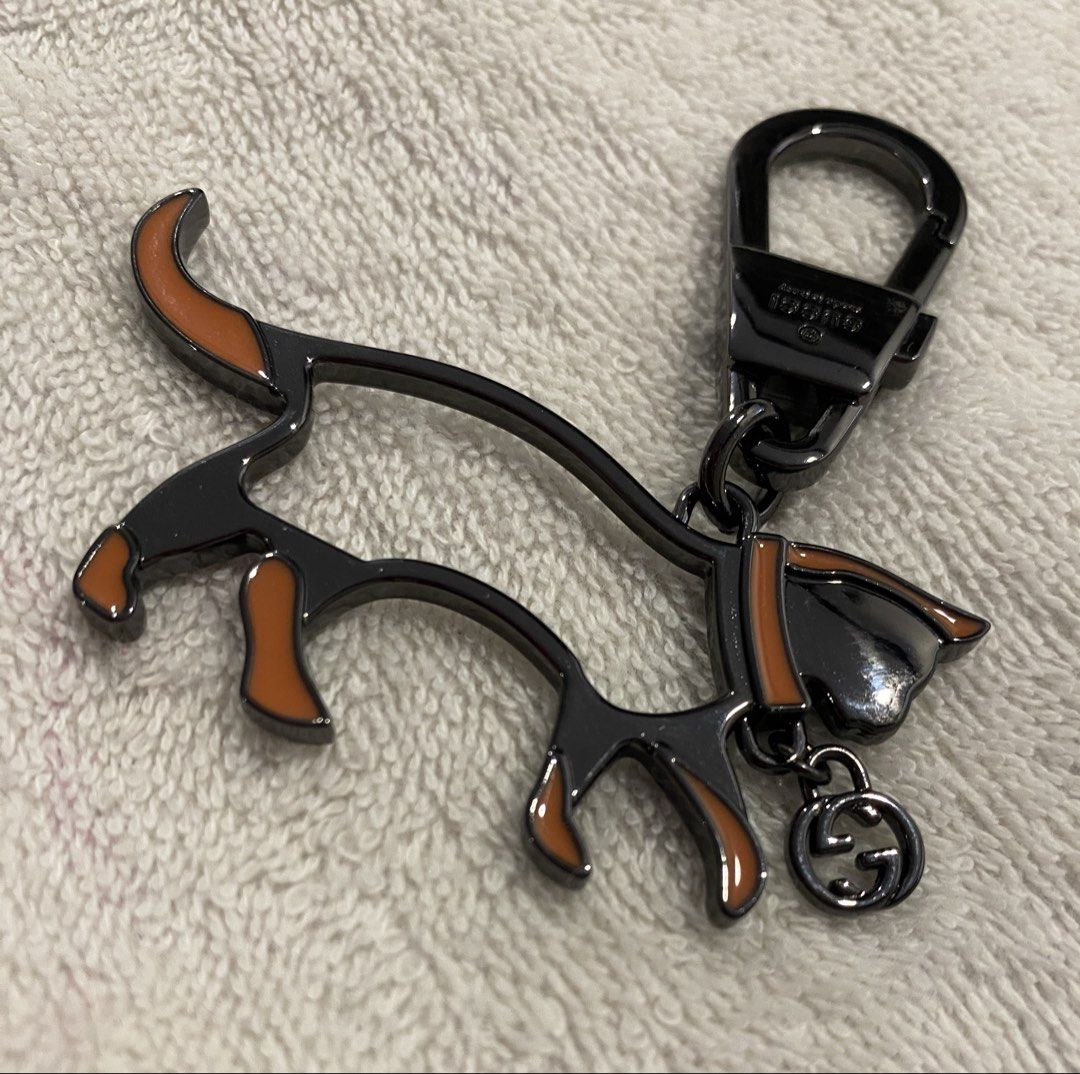 Gucci Cat Keychain Bag Charm (Category: Charms) located in Muntinlupa City. Submitted by mj.finds (Listing ID 1470461997, Image 2). Description: - Gucci cat keychain - Gunmetal hardware with orange enamel accents - Features a dangling Interlocking G logo charm - Engraved Gucci branding on the clasp - Heavy metal construction with a super sturdy hook - Great for styling handbags or using as a keyring.