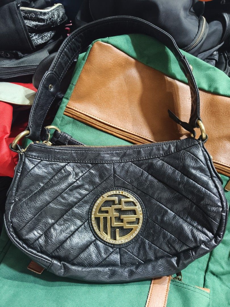 Guess black leather shoulder bag with gold hardware (Category: Shoulder Bags) located in Davao. Submitted by navil01 (Listing ID 1470489479, Image 1). Description: - Brand: Guess - Material: Black faux leather with quilted chevron front pattern - Hardware: Gold-tone hardware with a large round crystal rhinestone medallion logo - Strap: Single strap attached with brass rings - Interior: Colorful printed fabric lining with multi-colored Guess logos