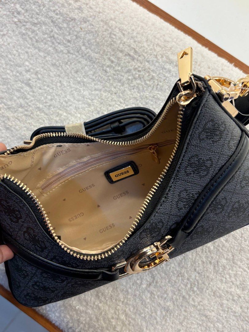 Guess Dea Top Zip Shoulder Bag (Category: Shoulder Bags) located in Taguig. Submitted by 02ruedasrh20304 (Listing ID 1470465050, Image 2). Description: - Authentic Guess shoulder bag in sleek black monogram design. - Features eye-catching gold-tone hardware and prominent front G logo buckle. - Clean cream fabric interior with repeating Guess branding. - Includes practical interior zip pocket and slip compartments. - Comes with an extra brand-new 