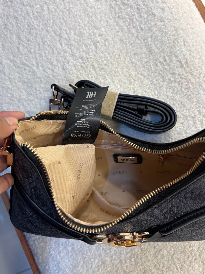 Guess Dea Top Zip Shoulder Bag (Category: Shoulder Bags) located in Taguig. Submitted by 02ruedasrh20304 (Listing ID 1470465050, Image 3). Description: - Authentic Guess shoulder bag in sleek black monogram design. - Features eye-catching gold-tone hardware and prominent front G logo buckle. - Clean cream fabric interior with repeating Guess branding. - Includes practical interior zip pocket and slip compartments. - Comes with an extra brand-new 