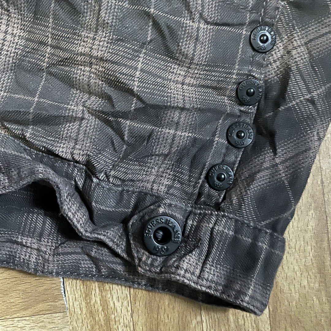 Guess Jeans Brown Plaid Cargo Shorts (Category: Shorts) located in Binan City. Submitted by peachilee (Listing ID 1470431870, Image 3). Description: - Brand: Guess Jeans - Color/Pattern: Brown and dark tones plaid - Fit: Mid-rise - Closure: Button fly with branded metal hardware - Style: Utility with front button details and zipped back pockets - Details: Guess Los Angeles leather patch on the back waistband - Fabric: Textured material with a dar