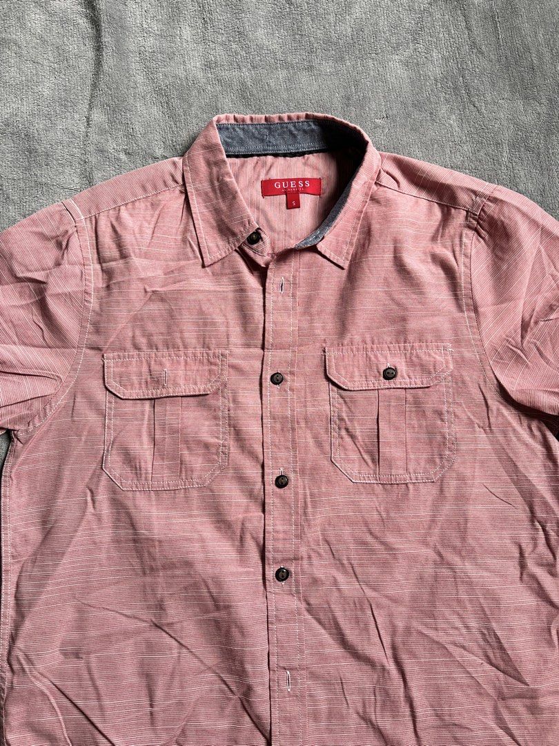 Guess Men Short Sleeve Button Down Shirt Pink Size S (Category: Tshirts & Polo Shirts ) located in Urdaneta. Submitted by m1k3yl (Listing ID 1470370113, Image 2). Description: - Brand: Guess - Style: Short sleeve button-down shirt - Color: Pink with subtle striped pattern - Size: Small (tag attached inside red neck label) - Details: Two chest pockets with button flaps, grey contrast lining on collar, and grey trim on cuffs - Fit/Material: Lightwe
