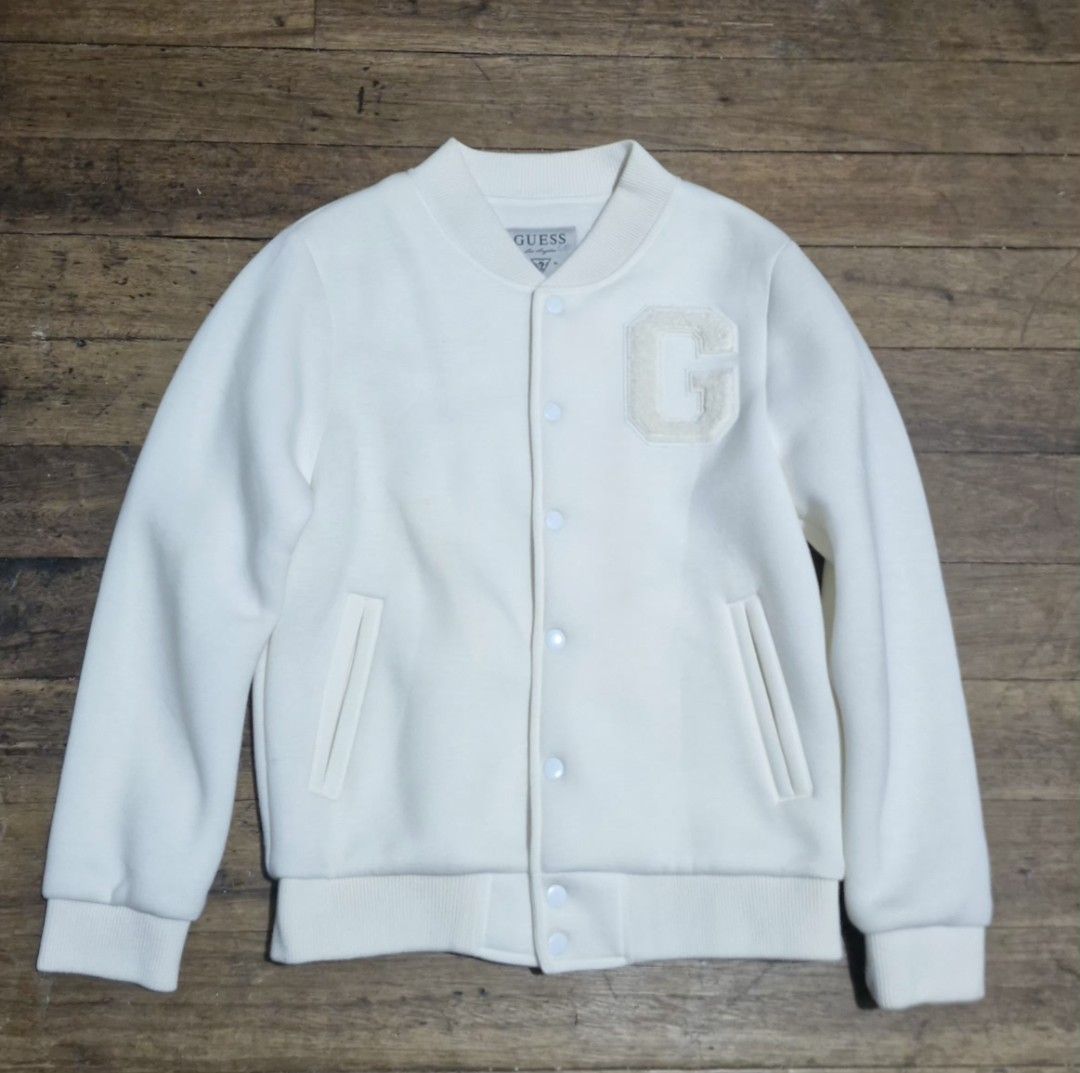 Guess White Varsity Jacket with Letter G (Category: Coats, Jackets and Outerwear) located in Manila. Submitted by blackstarharpoon (Listing ID 1470523000, Image 1). Description: - Brand: Guess - Item: Varsity Jacket - Color: Off-White - Closure: Snap button front - Pockets: Two side pockets - Design Details: Large chenille letter 'G' patch on the chest, ribbed collar, cuffs, and hem - Authenticity: Guess Los Angeles tag inside the collar - Condit