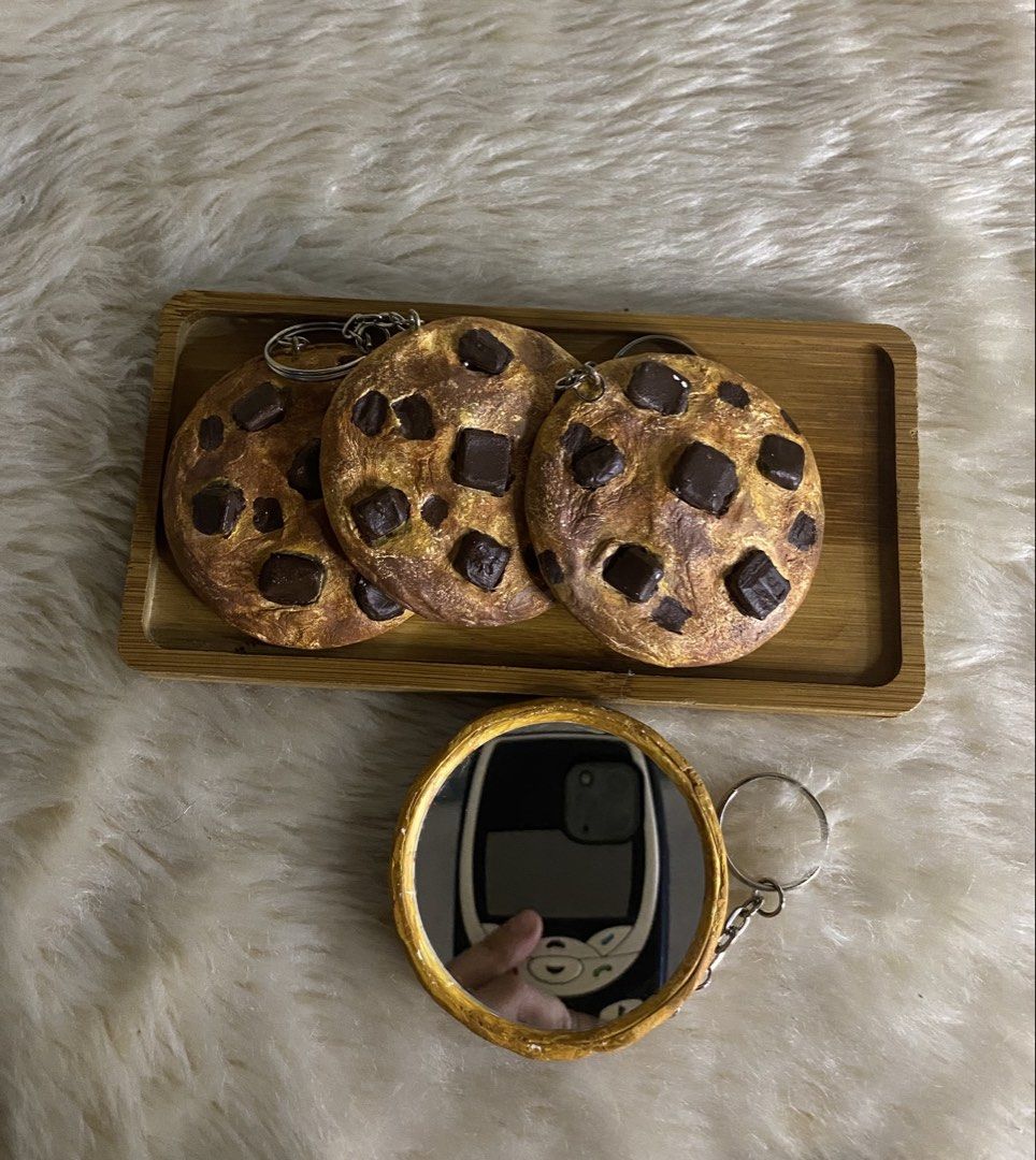 Handmade Cookie Mirror Keychain (Category: Charms) located in Manila. Submitted by littleatorie.studio (Listing ID 1470543955, Image 1). Description: - Handmade chocolate chip cookie round mirror keychain - Features a chic rim on the mirror and realistic baked texture with chunky chocolate pieces - Comes with secure silver keyrings attached to each piece - Versatile and fun accessory for bags, keys, or pouches - Great gift idea for sweet tooths a