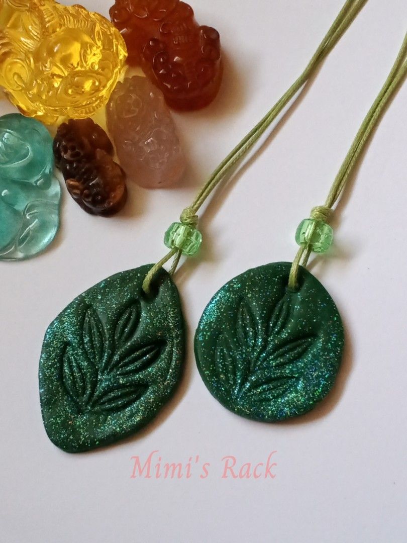 Handmade Green Glitter Leaf Clay Rope Necklace (Category: Necklaces) located in Taguig. Submitted by mimisrack (Listing ID 1470498196, Image 2). Description: 💚Add a touch of nature-inspired sparkle to your everyday look! This eye-catching necklace features a dark green leaf-shaped pendant with a beautifully embossed leaf design and dazzling multicolored glitter. Paired with a matching green cord and translucent green accent beads, it has a uniqu