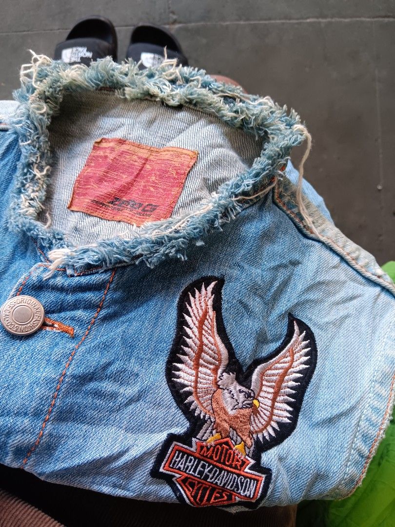 Harley Davidson Denim Vest With Eagle Patch (Category: Coats, Jackets and Outerwear) located in Cagayan de Oro. Submitted by kokirts17 (Listing ID 1470395242, Image 3). Description: - Style: Vintage light wash denim vest with a classic biker look - Details: Sleeveless with trendy raw frayed edges at the collar and armholes - Embroidery: Large Harley Davidson eagle patch on the back and a smaller one on the front chest pocket - Closure & Pockets: 