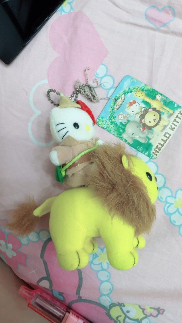 Hello Kitty Safari Lion Plush charm Keychain (Category: Plushies & Soft Toys) located in Quezon City. Submitted by lhewcifer (Listing ID 1470358288, Image 3). Description: - Rare Sanrio collectible featuring Kitty riding a yellow lion in an explorer outfit - Made with super soft, huggable fabric on both characters - Includes the original paper tag showing other animals from the safari collection - Equipped with a hanging chain at the top for easy