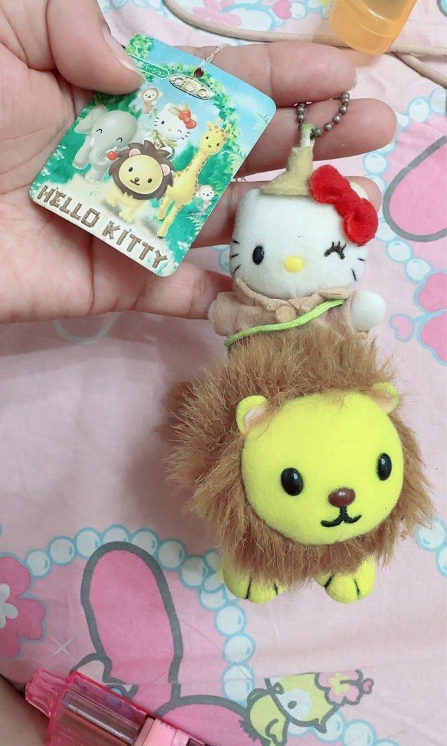 Hello Kitty Safari Lion Plush charm Keychain (Category: Plushies & Soft Toys) located in Quezon City. Submitted by lhewcifer (Listing ID 1470358288, Image 2). Description: - Rare Sanrio collectible featuring Kitty riding a yellow lion in an explorer outfit - Made with super soft, huggable fabric on both characters - Includes the original paper tag showing other animals from the safari collection - Equipped with a hanging chain at the top for easy