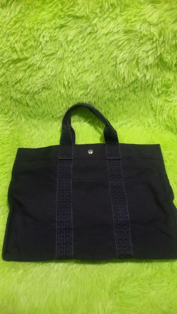 Hermes Gray Canvas Tote with Signature Webbed Straps (Category: Tote Bags) located in Manila. Submitted by twinklelyn03 (Listing ID 1470409918, Image 3). Description: - Authentic Hermes gray canvas tote bag - Signature webbed shoulder straps and convenient front slip pockets - Secure snap button closure at the top - Clean interior with a handy side zip pocket - Sturdy fabric construction that holds its shape well - Spacious and stylish casual eve