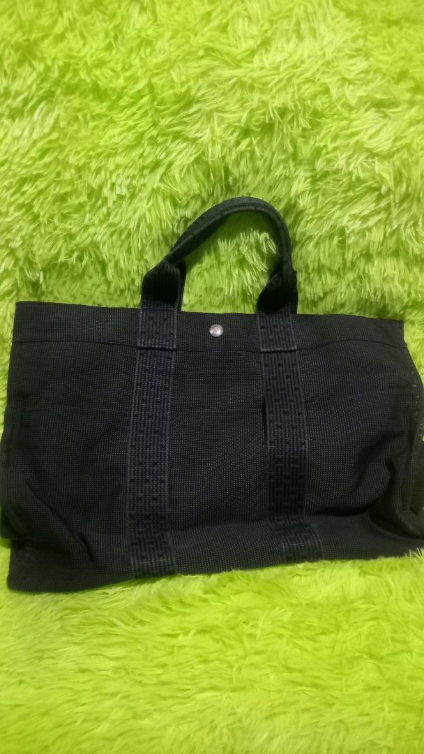 Hermes Gray Canvas Tote with Signature Webbed Straps (Category: Tote Bags) located in Manila. Submitted by twinklelyn03 (Listing ID 1470409918, Image 2). Description: - Authentic Hermes gray canvas tote bag - Signature webbed shoulder straps and convenient front slip pockets - Secure snap button closure at the top - Clean interior with a handy side zip pocket - Sturdy fabric construction that holds its shape well - Spacious and stylish casual eve
