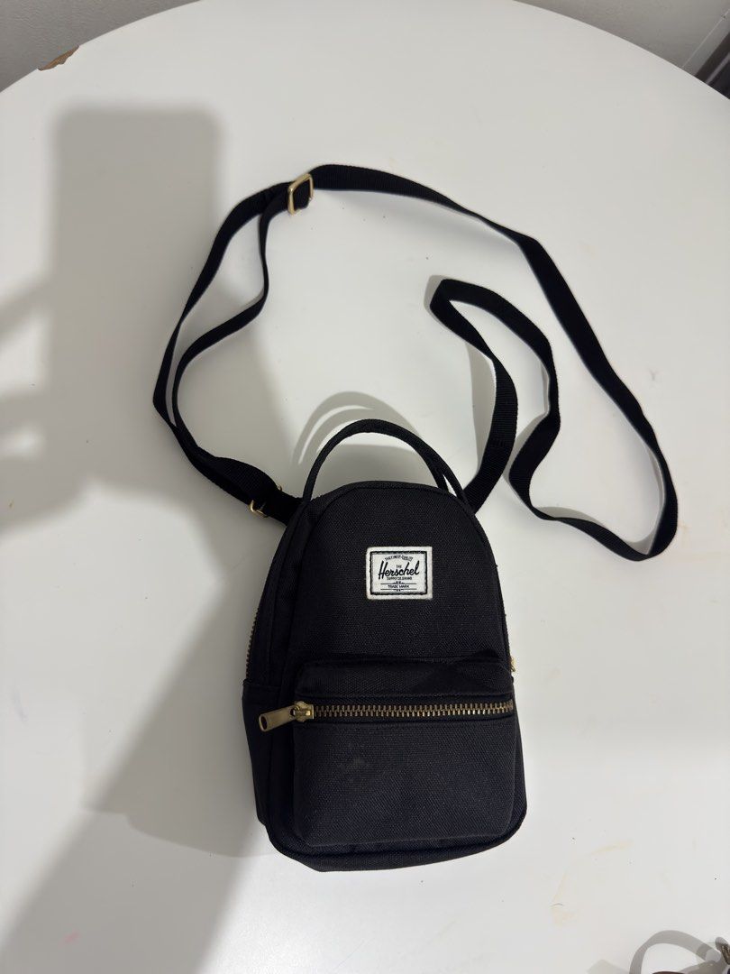 Herschel Supply Co. Mini Black Crossbody Backpack (Category: Cross-body Bags) located in Quezon City. Submitted by decluttergirlie (Listing ID 1470546614, Image 1). Description: - Authentic black Herschel mini backpack / crossbody bag - Brass zipper hardware and iconic branded label patch - Adjustable black strap and convenient top haul handle - Signature red and white striped fabric interior with slip pocket and branded tag - Compact and lightwe
