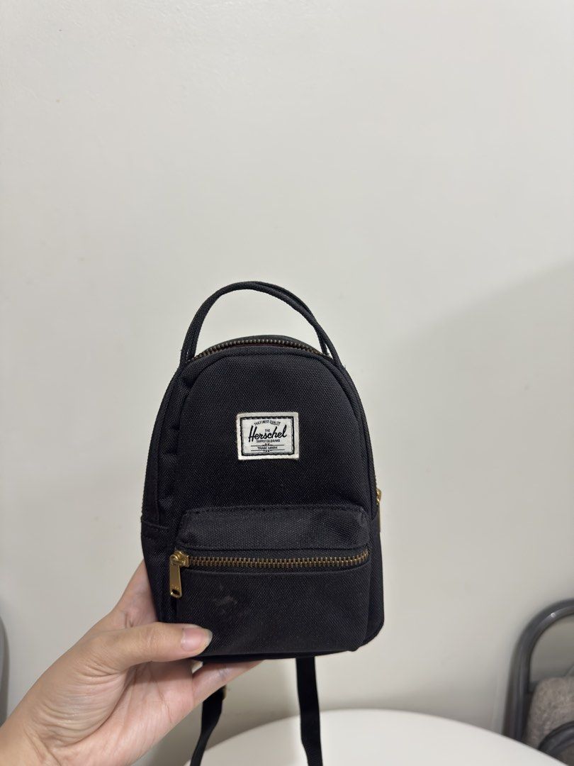 Herschel Supply Co. Mini Black Crossbody Backpack (Category: Cross-body Bags) located in Quezon City. Submitted by decluttergirlie (Listing ID 1470546614, Image 2). Description: - Authentic black Herschel mini backpack / crossbody bag - Brass zipper hardware and iconic branded label patch - Adjustable black strap and convenient top haul handle - Signature red and white striped fabric interior with slip pocket and branded tag - Compact and lightwe