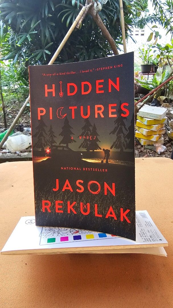 Hidden Pictures - Jason Rekulak (Category: Storybooks) located in Puerto Princesa. Submitted by tr1na (Listing ID 1470438064, Image 1). Description: - Title: Hidden Pictures - Author: Jason Rekulak - Format: Paperback (Flatiron Books) - Genre: Thriller / Mystery / Suspense - Plot: A gripping story about babysitting, eerie sketches, and dark secrets - Condition: Spine intact, pages clean - Cover: Bold red and black design with pine tree graphics.