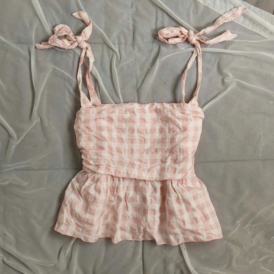 H&M Pink Gingham Tie Strap Peplum Top (Category: Sleeveless) located in Manila. Submitted by electricpetals (Listing ID 1470474907, Image 1). Description: - Design: Pink and white gingham pattern with a flared peplum hem - Straps: Self-tie ribbon straps at the shoulders - Fit & Comfort: Stretchy smocked bodice, light and textured fabric - Size: M-L .