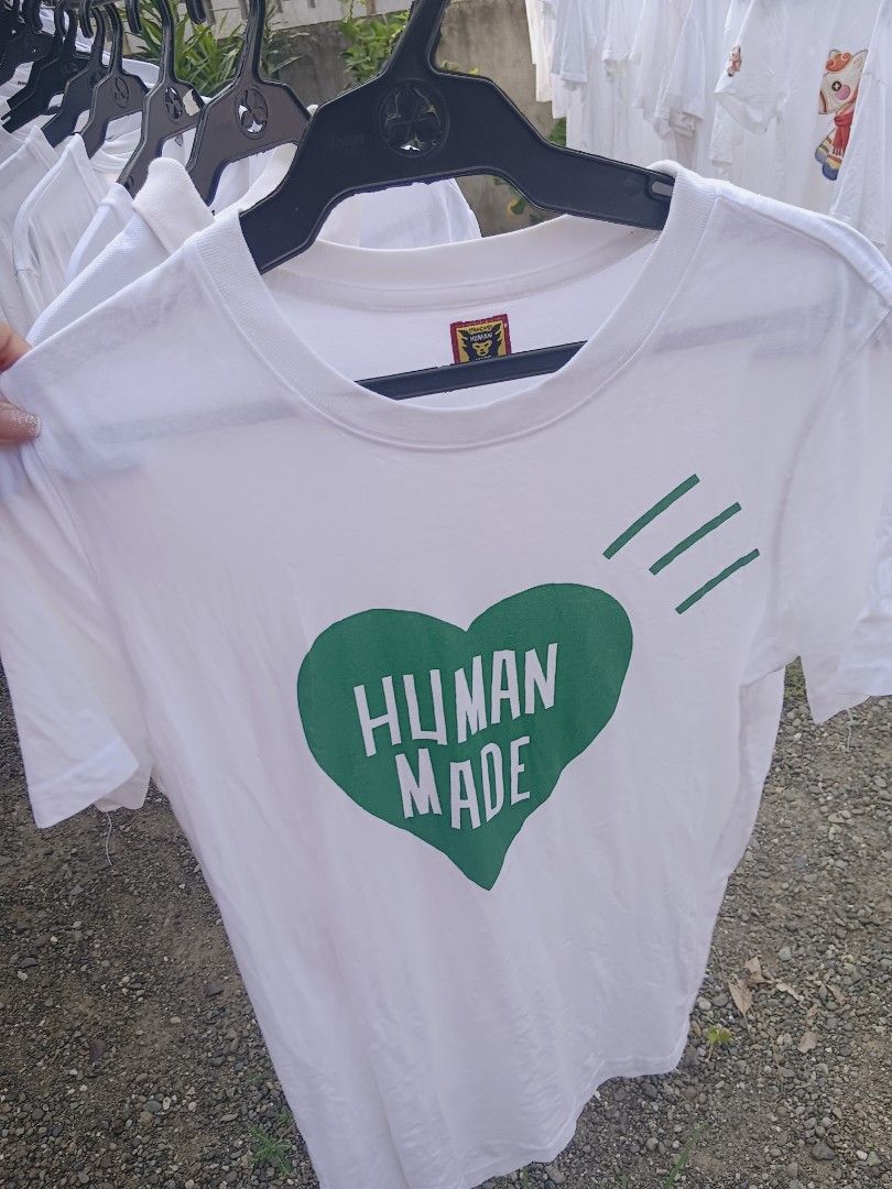 Human Made Green Heart White T-Shirt (Category: Shirts) located in Gapan. Submitted by athenascarlet (Listing ID 1470481321, Image 1). Description: - Brand: Human Made - Color: Clean White - Design: Large green heart graphic on chest with white text and three green slash marks above - Fit/Style: Classic crew neck and short sleeves - Condition: Ready to wear, collar tag intact.