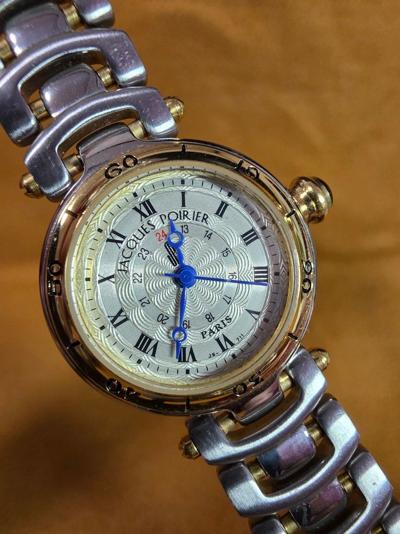 Jacques Poirier Paris Two-Tone Wristwatch (Category: Women's Watches) located in Rosales. Submitted by akumie30 (Listing ID 1470528823, Image 1). Description: - Brand: Jacques Poirier Paris - Dial: Textured silver with classic Roman numerals and inner 24-hour ring - Hands: Elegant blue hands - Details: Crown topped with a stylish dark cabochon stone - Bracelet: Two-tone links in steel and gold finish - Case Back: Stainless steel with 5 bar water 