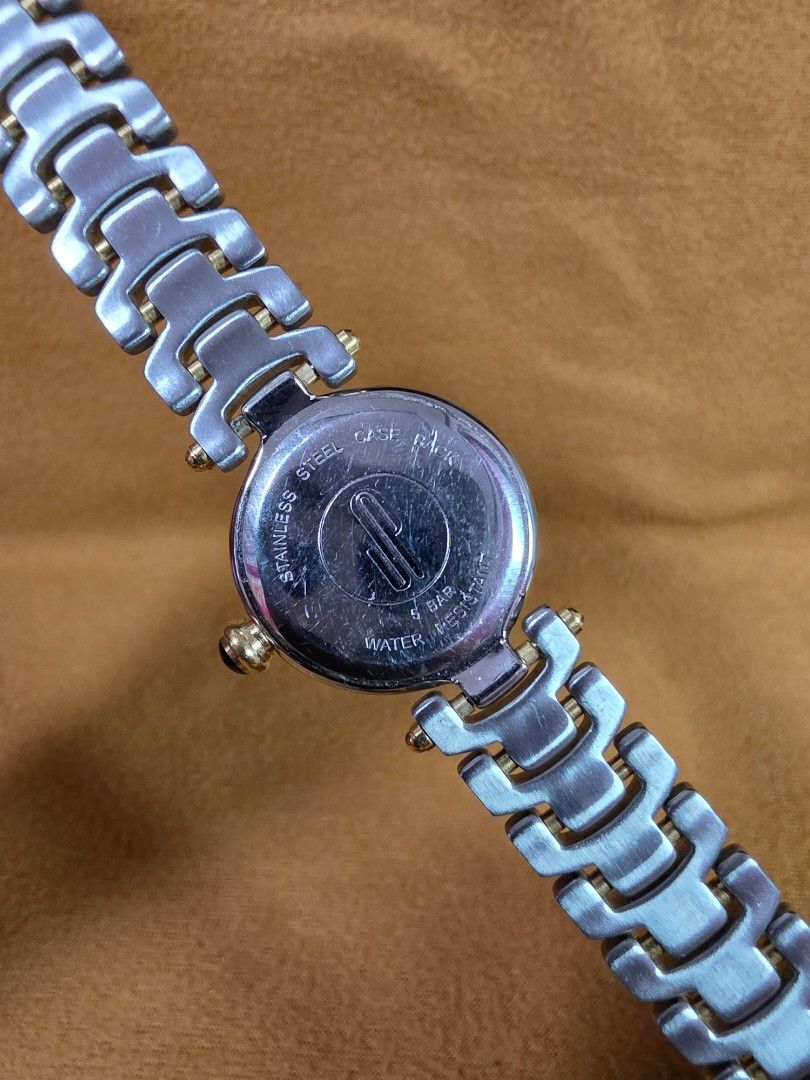 Jacques Poirier Paris Two-Tone Wristwatch (Category: Women's Watches) located in Rosales. Submitted by akumie30 (Listing ID 1470528823, Image 3). Description: - Brand: Jacques Poirier Paris - Dial: Textured silver with classic Roman numerals and inner 24-hour ring - Hands: Elegant blue hands - Details: Crown topped with a stylish dark cabochon stone - Bracelet: Two-tone links in steel and gold finish - Case Back: Stainless steel with 5 bar water 