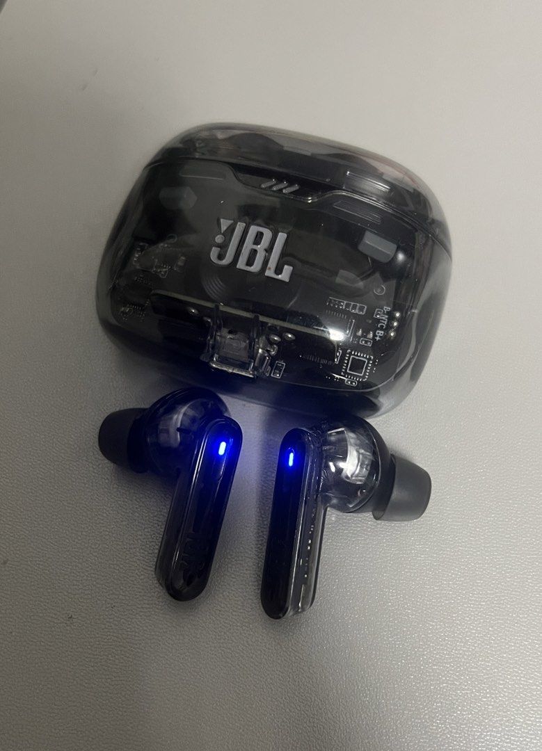 JBL Transparent Wireless Earbuds Charging Case (Category: Earphones) located in Marilao. Submitted by maygomez05 (Listing ID 1470468397, Image 1). Description: - No box included - Transparent black casing and visible circuit board - Features the prominent JBL logo on the front - Stem-style earbuds with glowing blue LED indicator lights - Compact charging case that easily fits in your hand or pocket - Stylish and reliable everyday audio accessory.