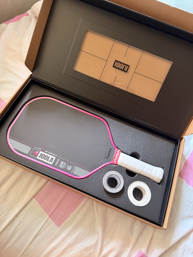 JOOLA Magnus IV 14mm Pickleball Paddle (Category: Racket and Ball Sports) located in Quezon City. Submitted by mamamiaaa15 (Listing ID 1470385256, Image 1). Description: JOOLA Magnus 3 14mm pickleball paddle, Tyson McGuffin edition. Pink trim and black face. Complete in original branded box with accessories and extra tape rolls included. Unused condition, stored properly inside packaging..