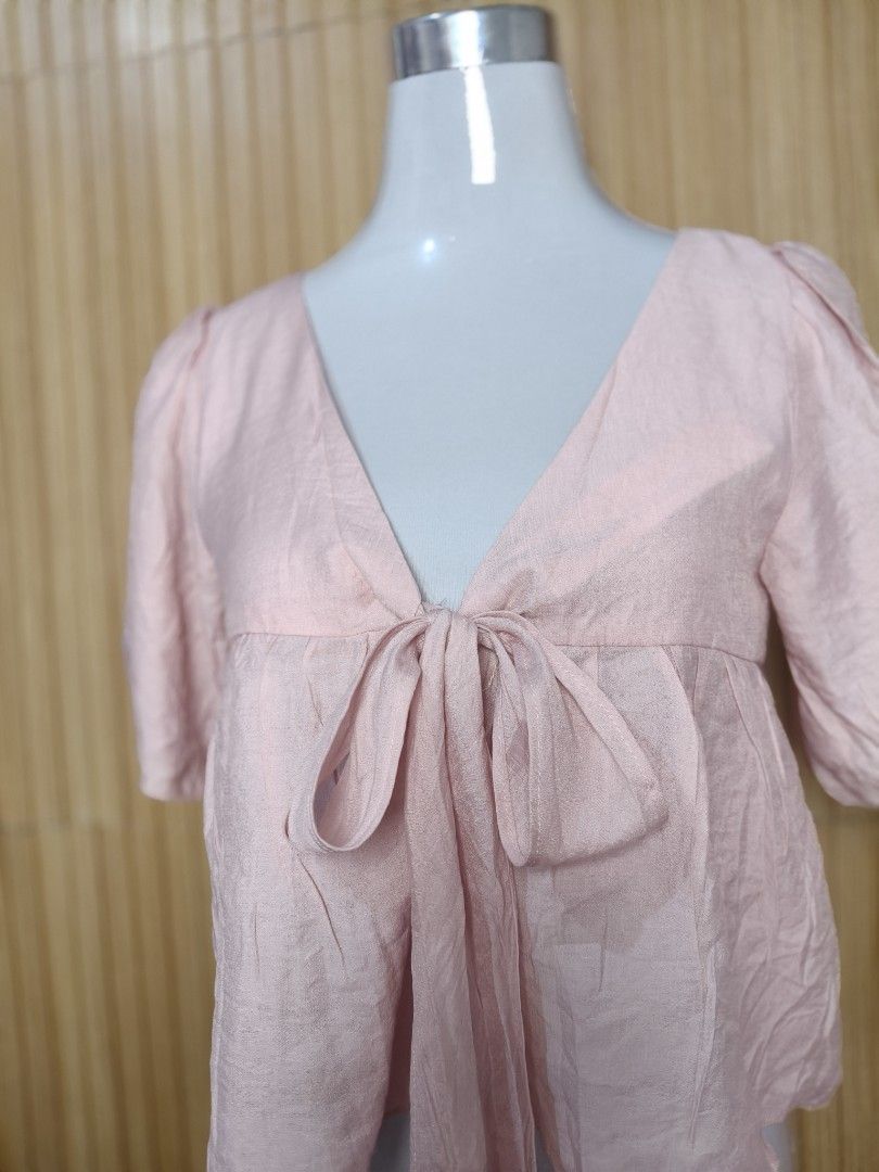 Kashieca Pink Front Tie Blouse Medium (Category: Blouses) located in Taguig. Submitted by ashie_clothing (Listing ID 1470367266, Image 2). Description: - Brand: Kashieca - Size: Medium - Color: Pink with a slight textured sheen - Style: V-neck, short sleeves, front tie closure - Condition: Brand new with original tag attached - Versatility: Great for casual wear or dressing up.