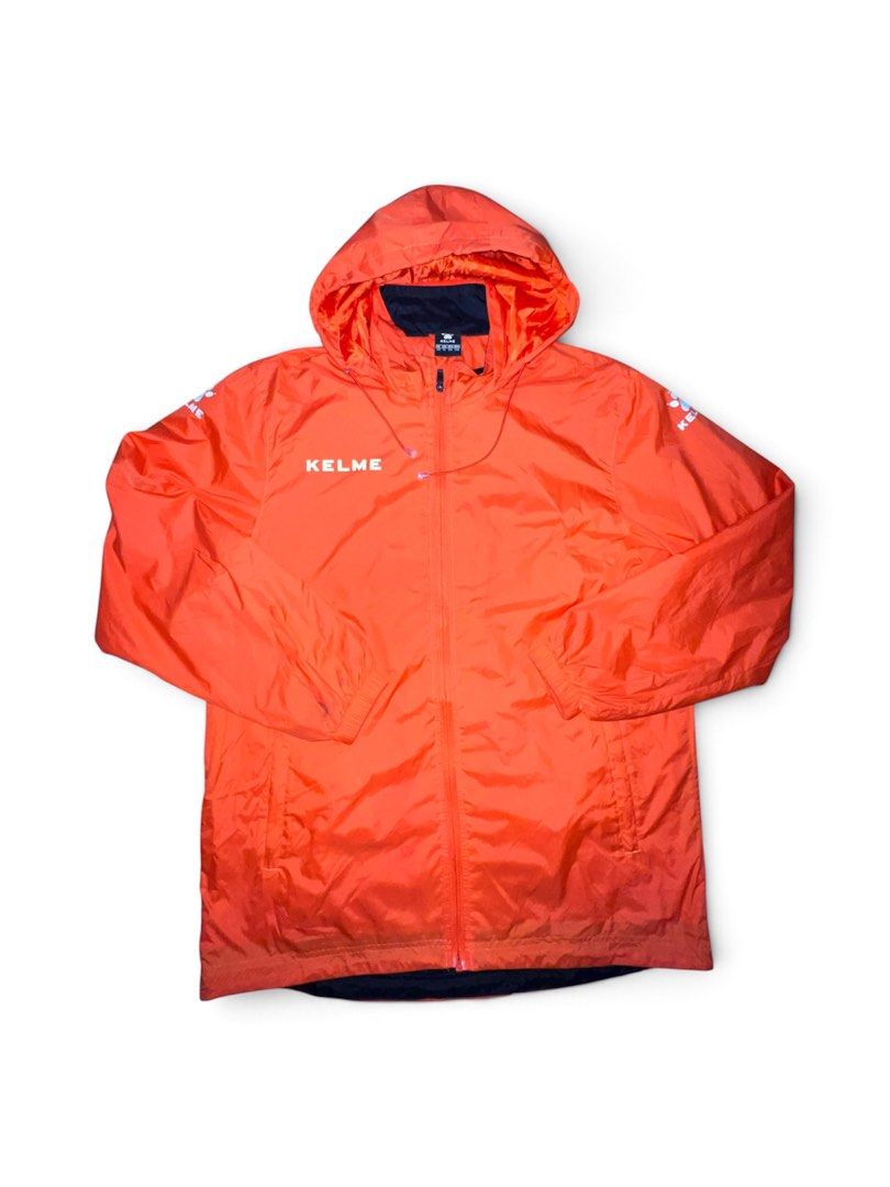 Kelme Orange Hooded Windbreaker Jacket (Category: Coats, Jackets and Outerwear) located in Binan City. Submitted by huntwear_.turtle (Listing ID 1470352489, Image 1). Description: - Vibrant bright orange Kelme windbreaker with a built-in hood - Lightweight material, ideal for workouts or breezy weather - Full front zip closure with adjustable drawstrings at the neck - White Kelme logo branding on the right chest and shoulders - Contrast black inn