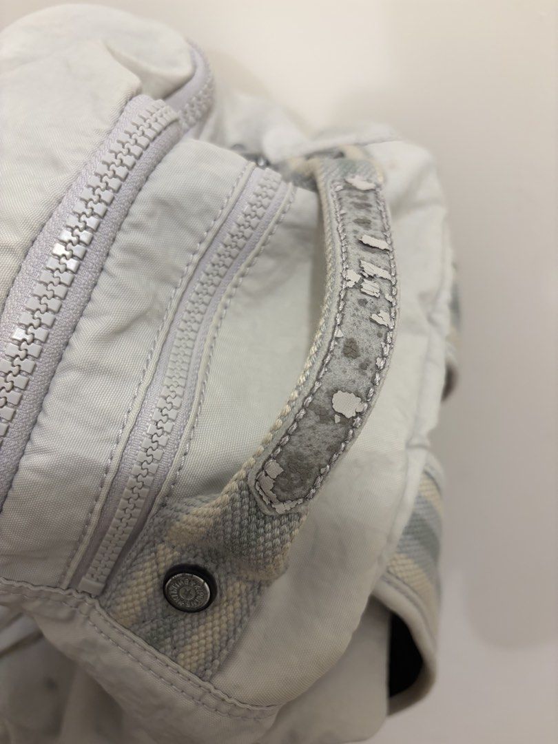 Kipling | Grey nylon backpack （分類：背囊）位於 Hong Kong。 由 juebtaglher 提交（商品編號 1470481663，圖片 2）。簡介： Kipling backpack in grey nylon. Round logo patch on front zip pocket. Double zipper compartment, top grab handle, side pockets. Heavy flaking and peeling visible on the top grab handle coating. Straps attached. Casual everyday bag with noticeable wear on handle trim.。