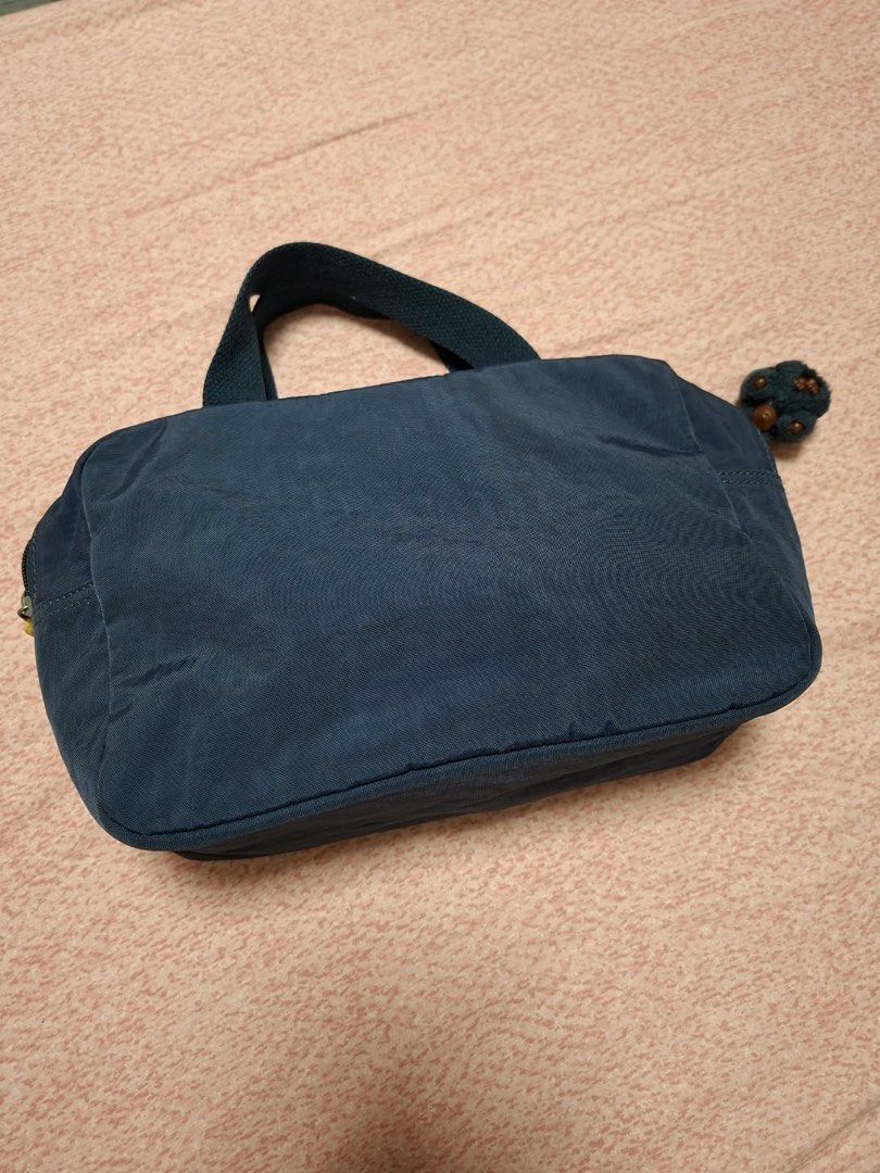 Kipling Navy Blue Handbag Tote Lunch Bag (Category: Tote Bags) located in Quezon City. Submitted by fishkeep3r (Listing ID 1470502855, Image 3). Description: - Authentic navy blue Kipling tote bag - Features secure top zip closure and sturdy top handles - Includes the iconic furry monkey keychain charm - Clean, wipe-clean metallic silver interior lining - Compact size: approximately 10 inches wide - Classic round Kipling logo patch on the front -