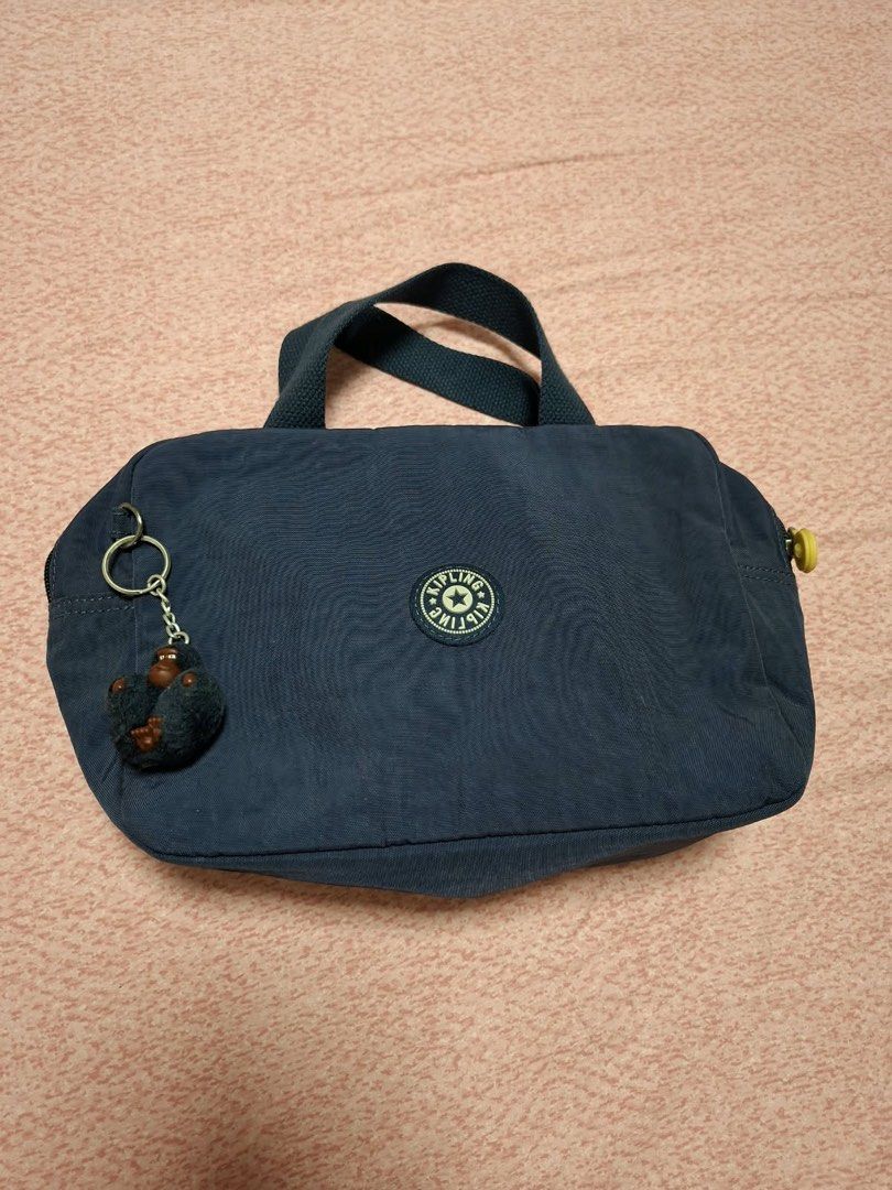 Kipling Navy Blue Handbag Tote Lunch Bag (Category: Tote Bags) located in Quezon City. Submitted by fishkeep3r (Listing ID 1470502855, Image 1). Description: - Authentic navy blue Kipling tote bag - Features secure top zip closure and sturdy top handles - Includes the iconic furry monkey keychain charm - Clean, wipe-clean metallic silver interior lining - Compact size: approximately 10 inches wide - Classic round Kipling logo patch on the front -