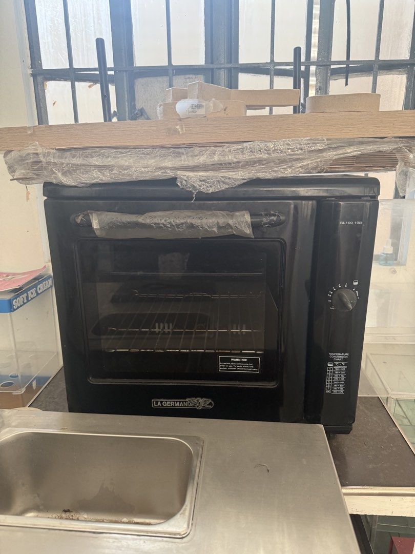 La Germania SL100 10B Black Oven (Category: Ovens & Toasters) located in Imus. Submitted by neirasalonga_ (Listing ID 1470441420, Image 2). Description: - Brand: La Germania - Model: SL100 10B - Color: Sleek black with glass door and metal handle - Controls: Rotary temperature knob with built-in conversion chart - Interior: Clean condition with wire rack and side baking tray supports - Condition: Ready for kitchen use.